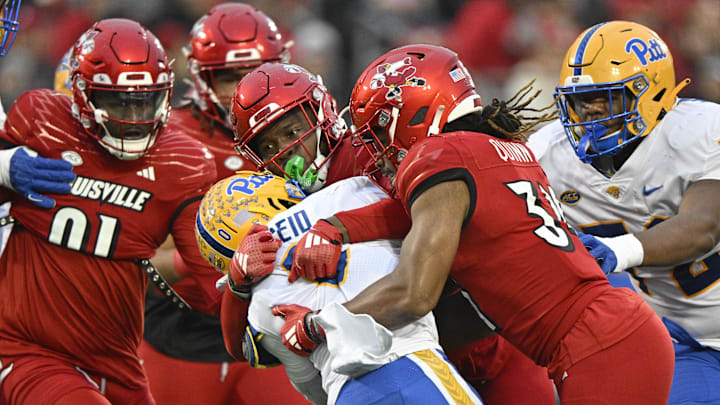 Nov 23, 2024; Louisville, Kentucky, USA;  Louisville Cardinals linebacker Stanquan Clark (6) and linebacker TJ Quinn (34) tackle Pittsburgh Panthers running back Desmond Reid (0) during the first half at L&N Federal Credit Union Stadium. 
