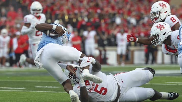 Sep 6, 2025; Houston, Texas, USA; Houston Cougars defensive lineman Carlos Allen Jr. (5) attempts to tackle Rice Owls quarterback Chase Jenkins (4) during the first quarter at Rice Stadium. Mandatory Credit: Troy Taormina-Imagn Images