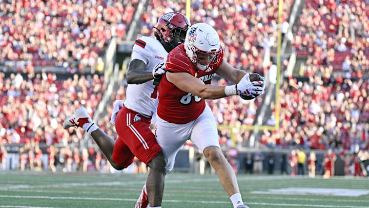 Sep 7, 2024; Louisville, Kentucky, USA;  Louisville Cardinals tight end Mark Redman (83) scores a touchdown under the pressure of Jacksonville State Gamecocks linebacker Jibreel Al-Amin (15) during the second half at L&N Federal Credit Union Stadium. Louisville defeated Jacksonville State 49-14. Mandatory Credit: Jamie Rhodes-Imagn Images