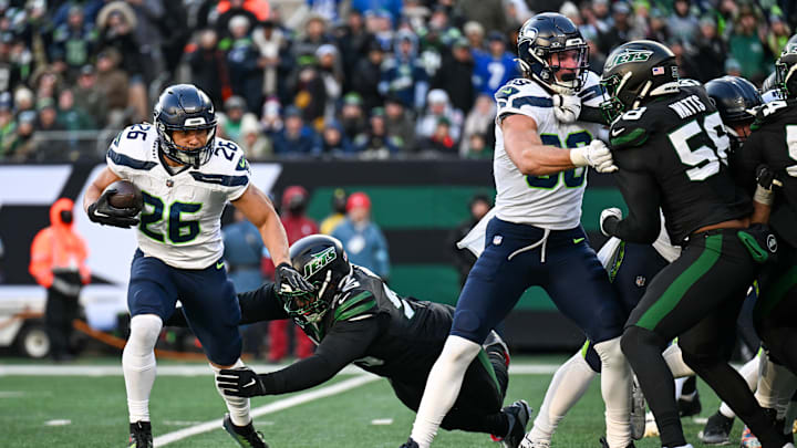 Dec 1, 2024; East Rutherford, New Jersey, USA; Seattle Seahawks running back Zach Charbonnet (26) runs with the ball and avoids a tackle by New York Jets defensive tackle Leonard Taylor III (96) during the third quarter at MetLife Stadium. Dec 1, 2024; East Rutherford, New Jersey, USA; Seattle Seahawks running back Zach Charbonnet (26) runs with the ball and avoids a tackle by New York Jets defensive tackle Leonard Taylor III (96) during the third quarter at MetLife Stadium.