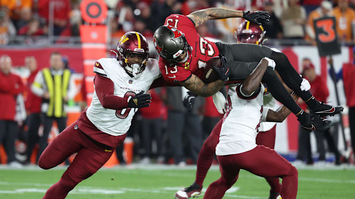 Jan 12, 2025; Tampa, Florida, USA; Tampa Bay Buccaneers wide receiver Mike Evans (13) is tackled by Washington Commanders safety Quan Martin (20) and linebacker Dante Fowler Jr. (6) during the third quarter of a NFC wild card playoff at Raymond James Stadium. Jan 12, 2025; Tampa, Florida, USA; Tampa Bay Buccaneers wide receiver Mike Evans (13) is tackled by Washington Commanders safety Quan Martin (20) and linebacker Dante Fowler Jr. (6) during the third quarter of a NFC wild card playoff at Raymond James Stadium.