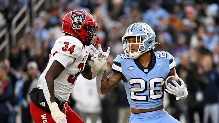 Nov 30, 2024; Chapel Hill, North Carolina, USA; North Carolina Tar Heels running back Omarion Hampton (28) with the ball as North Carolina State Wolfpack linebacker Kamal Bonner (34) defends in the first quarter at Kenan Memorial Stadium. Nov 30, 2024; Chapel Hill, North Carolina, USA; North Carolina Tar Heels running back Omarion Hampton (28) with the ball as North Carolina State Wolfpack linebacker Kamal Bonner (34) defends in the first quarter at Kenan Memorial Stadium.