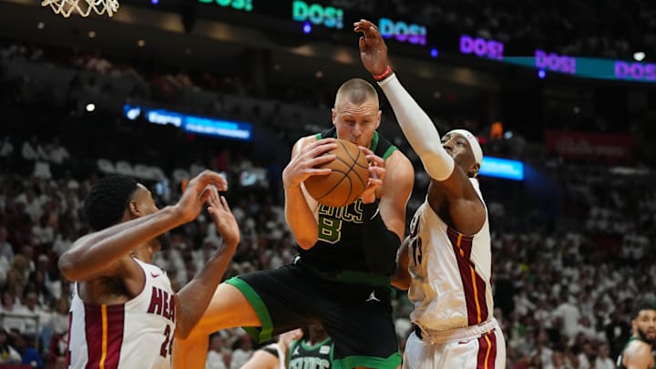 Apr 27, 2024; Miami, Florida, USA; Boston Celtics center Kristaps Porzingis (8) grabs a rebound over Bam Adebayo - Jim Rassol/USA TODAY Sports