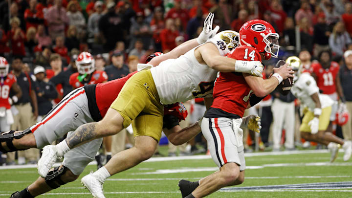 Jan 2, 2025; New Orleans, LA, USA; Georgia Bulldogs quarterback Gunner Stockton (14) runs with the ball during the second half as Notre Dame Fighting Irish defensive lineman Donovan Hinish (41) goes for a tackle at Caesars Superdome. Mandatory Credit: Amber Searls-Imagn Images