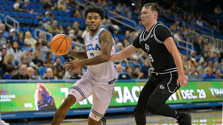 Dec 19, 2025; Los Angeles, California, USA; UCLA Bruins guard Donovan Dent (2) is defended by Cal Poly Mustangs guard Peter Bandelj (9) as he drives to the basket during the first half at Pauley Pavilion 