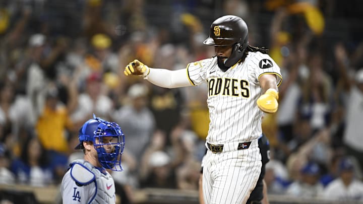 Aug 23, 2025; San Diego, California, USA; San Diego Padres right fielder Fernando Tatis Jr. (23) celebrates as he scores as Los Angeles Dodgers catcher Will Smith (16) looks on during the eighth inning at Petco Park. Mandatory Credit: Denis Poroy-Imagn Images
