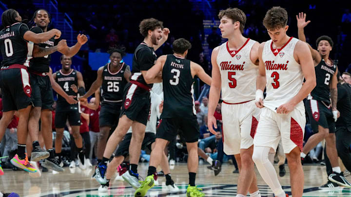 Miami RedHawks guard Peter Suder (5) and guard Luke Skaljac (3) leave the floor as UMass Minutemen forward Leonardo Bettiol (3) celebrates a win after the final buzzer of the second half of Mid-American Conference Tournament first round game between the Miami RedHawks and the UMass Minutemen at Rocket Arena in Cleveland on Thursday, March 12, 2026. Top-seeded Miami was eliminated from the tournament with an 87-82 loss to the Minutemen.