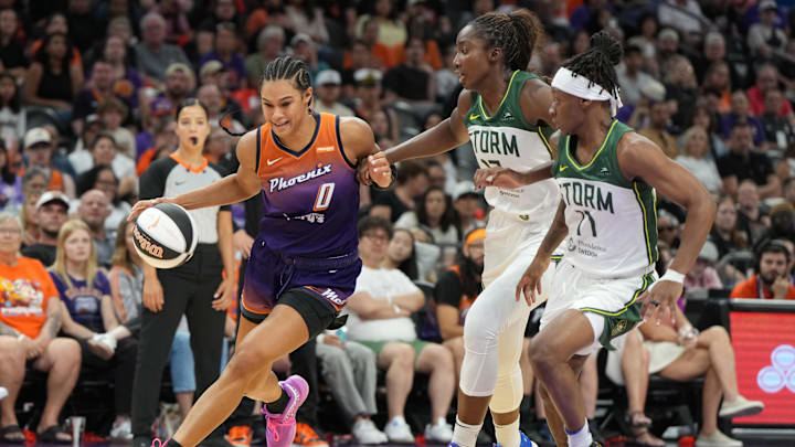 Jun 7, 2025; Phoenix, Arizona, USA; Phoenix Mercury forward Satou Sabally (0) drives around Seattle Storm forward Ezi Magbegor (13) and guard Erica Wheeler (17) in the second half at Footprint Center. Mandatory Credit: Rick Scuteri-Imagn Images
