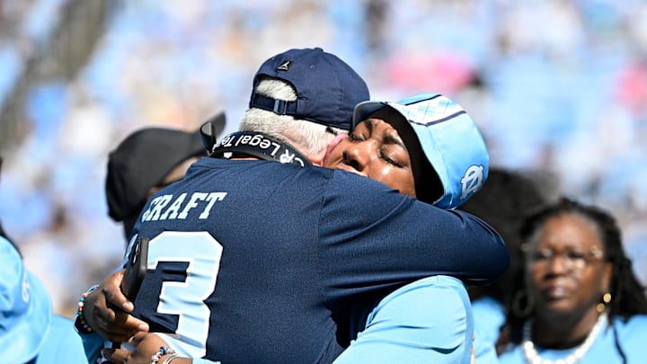 Oct 12, 2024; Chapel Hill, North Carolina, USA;  North Carolina Tar Heels head coach Mack Brown and September Craft hug during a tribute to former player Tylee Craft who died of Lung Cancer. Mandatory Credit: Bob Donnan-Imagn Images
