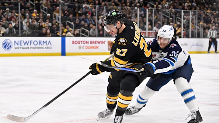 Mar 19, 2026; Boston, Massachusetts, USA; Winnipeg Jets center Morgan Barron (36) challenges Boston Bruins defenseman Hampus Lindholm (27) for the puck during the second period at TD Garden. Mandatory Credit: Eric Canha-Imagn Images