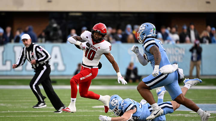 Nov 30, 2024; Chapel Hill, North Carolina, USA; North Carolina State Wolfpack wide receiver Kevin Concepcion (10) with the ball as North Carolina Tar Heels linebacker Caleb LaVallee (34) and linebacker Amare Campbell (17) defend in the first quarter at Kenan Memorial Stadium. Mandatory Credit: Bob Donnan-Imagn Images