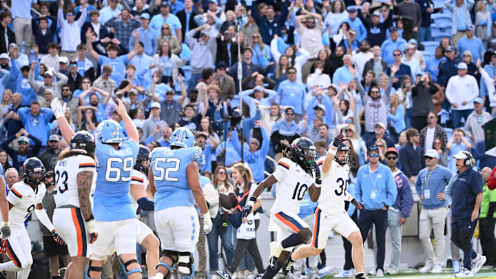 Oct 25, 2025; Chapel Hill, North Carolina, USA; North Carolina Tar Heels and Virginia Cavaliers players react at the end of overtime at Kenan Stadium. Mandatory Credit: Bob Donnan-Imagn Images