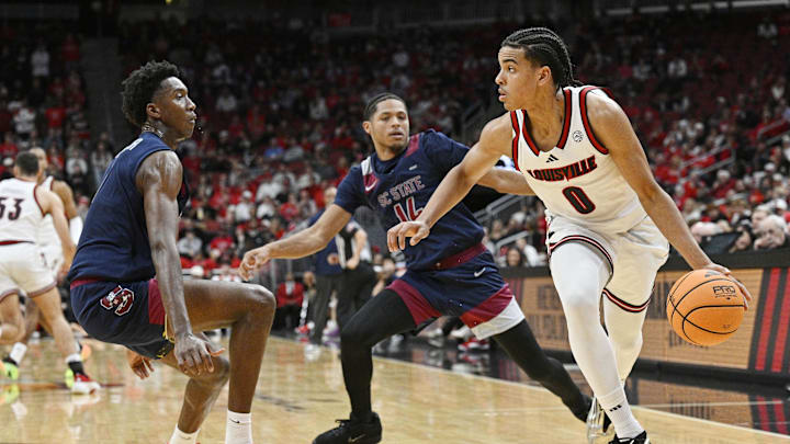 Nov 3, 2025; Louisville, Kentucky, USA;  Louisville Cardinals guard Mikel Brown Jr. (0) dribbles against South Carolina State Bulldogs guard Derwin Hodge (7) and guard Jamal Miles (14) during the first half at KFC Yum! Center. Mandatory Credit: Jamie Rhodes-Imagn Images