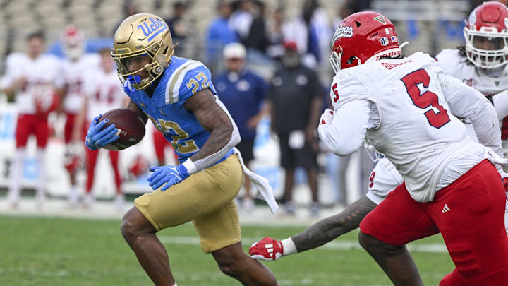 Nov 30, 2024; Pasadena, California, USA; UCLA Bruins running back Keegan Jones (22) runs past Fresno State Bulldogs linebacker Tuasivi Nomura (8) and Fresno State Bulldogs defensive lineman Devo Bridges (5) during the second quarter at Rose Bowl. Mandatory Credit: Robert Hanashiro-Imagn Images