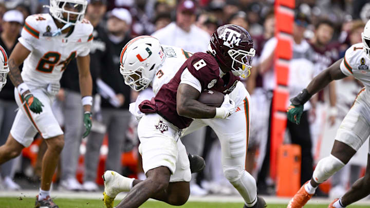 Dec 20, 2025; College Station, TX, USA; Texas A&M Aggies running back Le'Veon Moss (8) runs with the ball past Miami Hurricanes defensive lineman Akheem Mesidor (3) during the game between the Aggies and the Hurricanes at Kyle Field. Mandatory Credit: Jerome Miron-Imagn Images