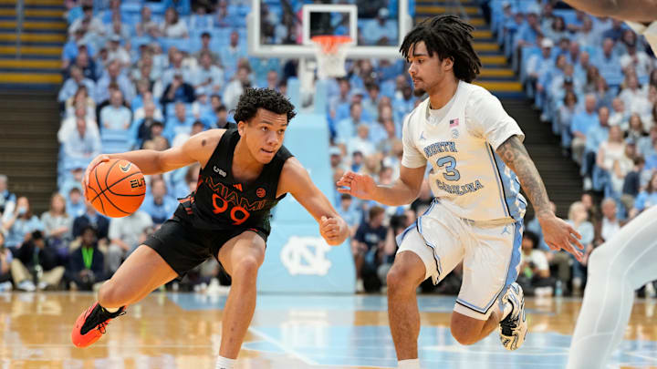 Mar 1, 2025; Chapel Hill, North Carolina, USA;  Miami (Fl) Hurricanes guard Divine Ugochukwu (99) with the ball as North Carolina Tar Heels guard Elliot Cadeau (3) defends in the first half at Dean E. Smith Center. Mandatory Credit: Bob Donnan-Imagn Images