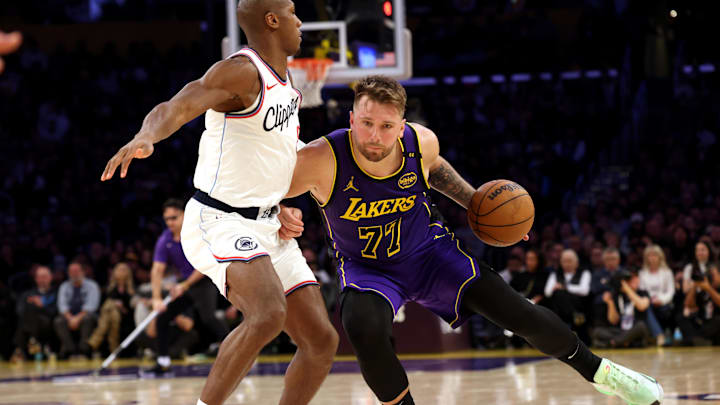 Feb 28, 2025; Los Angeles, California, USA; Los Angeles Lakers guard Luka Doncic (77) drives against LA Clippers guard Kris Dunn (8) during the fourth quarter at Crypto.com Arena. Mandatory Credit: Jason Parkhurst-Imagn Images