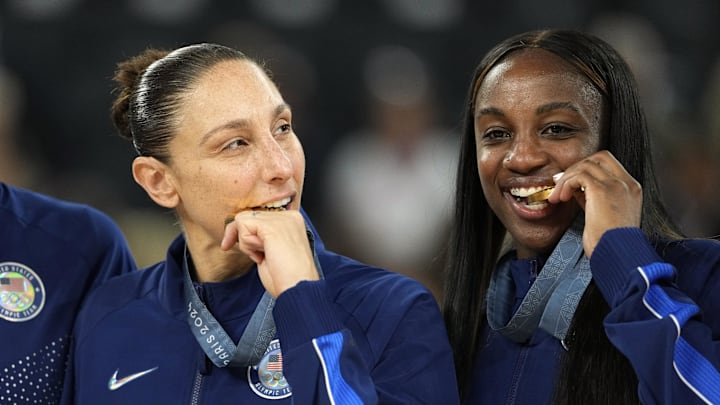 Aug 11, 2024; Paris, France; United States shooting guard Diana Taurasi (12) and guard Jackie Young (13) celebrate on the podium after defeating France in the women's gold medal game during the Paris 2024 Olympic Summer Games at Accor Arena. Mandatory Credit: Kyle Terada-Imagn Images