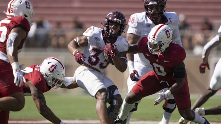 Oct 5, 2024; Stanford, California, USA;  Virginia Tech Hokies running back Bhayshul Tuten (33) spins away from Stanford Cardinal linebacker Gaethan Bernadel (0) during the third quarter at Stanford Stadium. Mandatory Credit: Stan Szeto-Imagn Images
