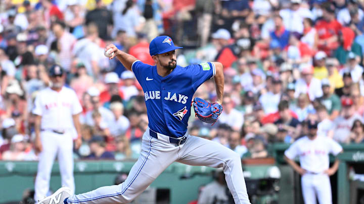 A baseball player in a blue and white uniform pitching a white baseball during a game. A baseball player in a blue and white uniform pitching a white baseball during a game.
