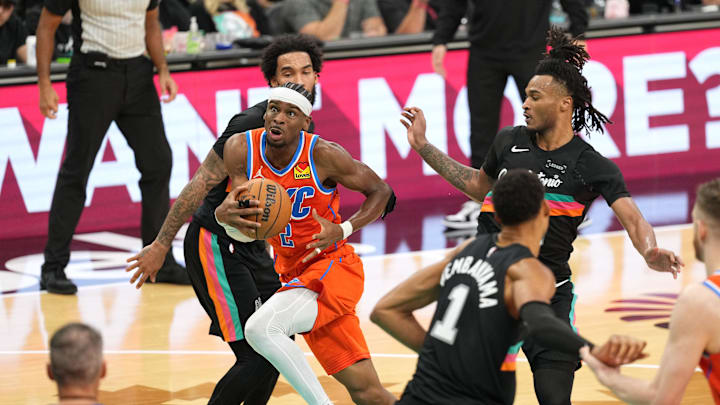 Dec 23, 2025; San Antonio, Texas, USA; Oklahoma City Thunder guard Shai Gilgeous-Alexander (2) drives to the basket past San Antonio Spurs guard Stephon Castle (5) and forward Julian Champagnie (30) during the second half at Frost Bank Center. Mandatory Credit: Scott Wachter-Imagn Images