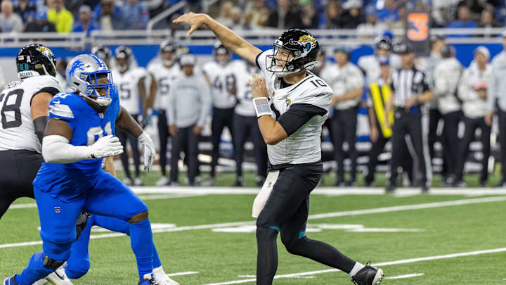 Nov 17, 2024; Detroit, Michigan, USA; Jacksonville Jaguars quarterback Mac Jones (10) passes the ball and is pressured by Detroit Lions defensive end Levi Onwuzurike (91) during the second half at Ford Field. Mandatory Credit: David Reginek-Imagn Images