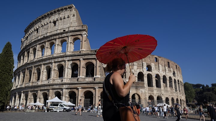 Tourists pass in front of the Colosseum in Rome, Italy