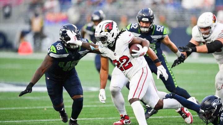 Arizona Cardinals running back Michael Carter rushes and stiff arms Seattle Seahawks linebacker Tyrice Knight.