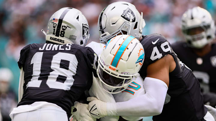 Nov 17, 2024; Miami Gardens, Florida, USA; Miami Dolphins wide receiver Tyreek Hill (10) runs with the football against Las Vegas Raiders cornerback Jack Jones (18) and defensive end Charles Snowden (49) during the third quarter at Hard Rock Stadium. Mandatory Credit: Sam Navarro-Imagn Images