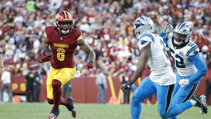 Oct 20, 2024; Landover, Maryland, USA; Washington Commanders running back Brian Robinson Jr. (8) carries the ball as Carolina Panthers cornerback Michael Jackson (2) and Panthers linebacker DJ Johnson (52) defends during the second half at Northwest Stadium. Mandatory Credit: Amber Searls-Imagn Images
