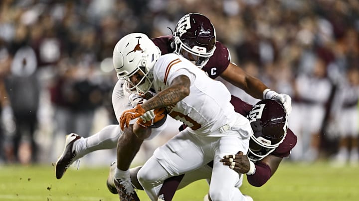 Nov 30, 2024; College Station, Texas, USA; Texas Longhorns wide receiver DeAndre Moore Jr. (0) is tackled by Texas A&M Aggies defensive lineman Nic Scourton (11) and linebacker Taurean York (21) during the first half at Kyle Field. Mandatory Credit: Maria Lysaker-Imagn Images 