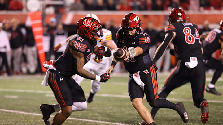 Nov 23, 2024; Salt Lake City, Utah, USA; Utah Utes quarterback Isaac Wilson (11) goes to hand the ball off to running back Mike Mitchell (21) against the Iowa State Cyclones during the third quarter at Rice-Eccles Stadium. Mandatory Credit: Rob Gray-Imagn Images