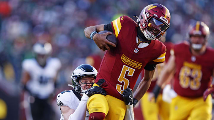 Dec 22, 2024; Landover, Maryland, USA; Washington Commanders quarterback Jayden Daniels (5) runs the ball against Philadelphia Eagles cornerback Cooper DeJean (33) during the third quarter at Northwest Stadium. Mandatory Credit: Peter Casey-Imagn Images