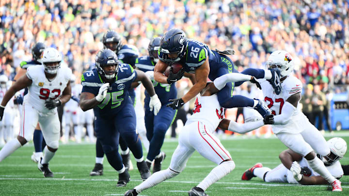 Nov 9, 2025; Seattle, Washington, USA; Seattle Seahawks running back Zach Charbonnet (26) leaps over Arizona Cardinals safety Jalen Thompson (34) for a touchdown during the second quarter at Lumen Field. Mandatory Credit: Steven Bisig-Imagn Images
