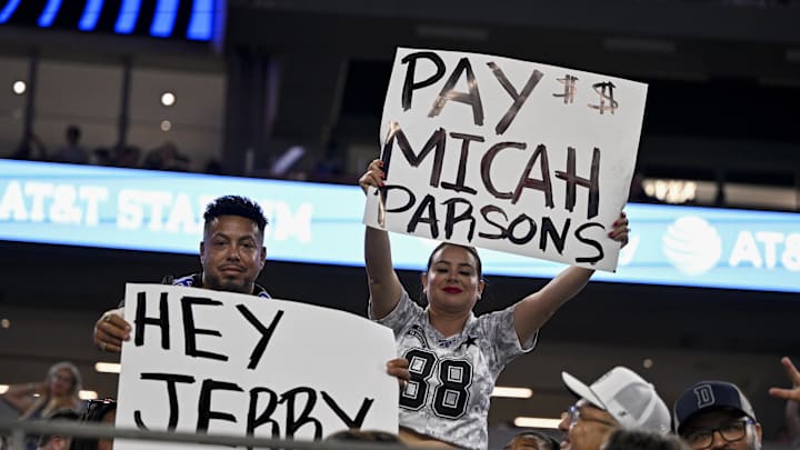 Aug 16, 2025; Arlington, Texas, USA; Dallas Cowboys fans hold up signs to owner Jerry Jones and defensive end Micah Parsons (11) during the second half of the game against the Baltimore Ravens at AT&T Stadium. Mandatory Credit: Jerome Miron-Imagn Images