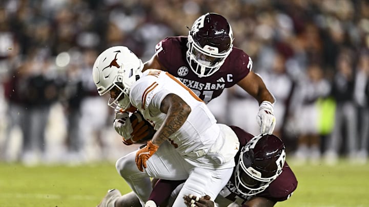 Nov 30, 2024; College Station, Texas, USA; Texas Longhorns wide receiver DeAndre Moore Jr. (0) is tackled by Texas A&M Aggies defensive lineman Nic Scourton (11) and linebacker Taurean York (21) during the first half at Kyle Field. Mandatory Credit: Maria Lysaker-Imagn Images 