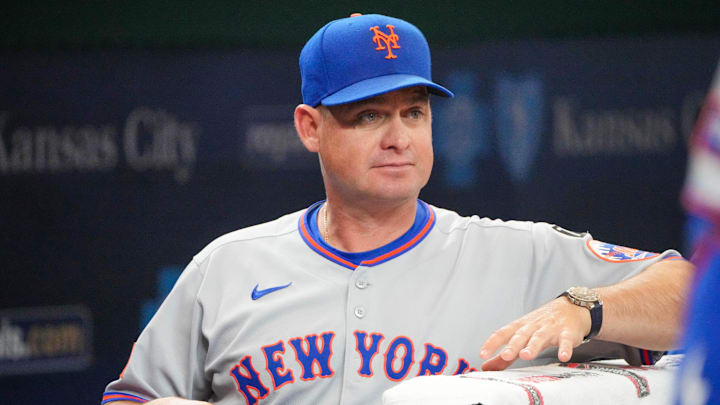 Jul 11, 2025; Kansas City, Missouri, USA; New York Mets manager Carlos Mendoza (64) watches from the dugout against the Kansas City Royals prior to a game at Kauffman Stadium. Mandatory Credit: Denny Medley-Imagn Images