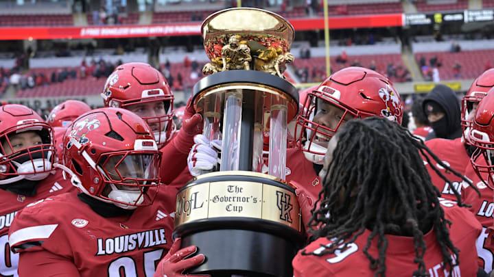 Nov 29, 2025; Louisville, Kentucky, USA;  Louisville Cardinals celebrate with the Governor’s Cup after defeating the Kentucky Wildcats at L&N Federal Credit Union Stadium. Louisville defeated Kentucky 41-0. Mandatory Credit: Jamie Rhodes-Imagn Images