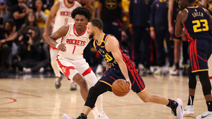Golden State Warriors guard Stephen Curry controls the ball against Houston Rockets forward/guard Amen Thompson.