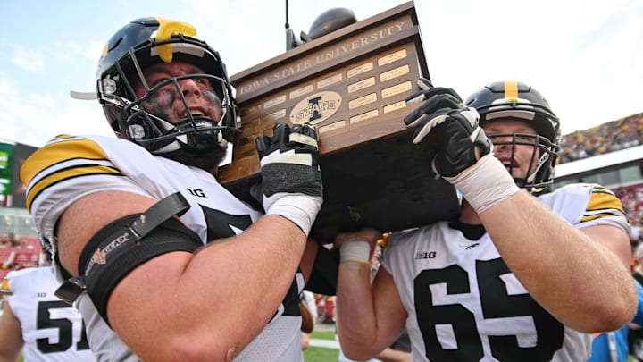 Sep 9, 2023; Ames, Iowa, USA; Iowa Hawkeyes offensive lineman Nick DeJong (56) and offensive lineman Logan Jones (65) carry the Cy-Hawk trophy after the game against the Iowa State Cyclones at Jack Trice Stadium. Mandatory Credit: Jeffrey Becker-Imagn Images