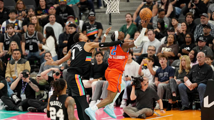 Dec 23, 2025; San Antonio, Texas, USA; Oklahoma City Thunder guard Shai Gilgeous-Alexander (2) draws a foul from San Antonio Spurs forward Victor Wembanyama (1) while driving to the basket during the first half at Frost Bank Center. Mandatory Credit: Scott Wachter-Imagn Images