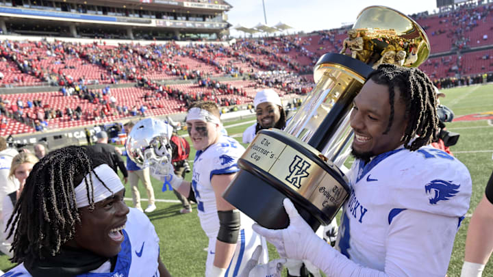 Nov 25, 2023; Louisville, Kentucky, USA;  Louisville Cardinals defensive back Gilbert Frierson (13) and defensive back Maxwell Hairston (31) celebrated with the Governor   s Cup following the second half against the Louisville Cardinals at L&N Federal Credit Union Stadium. Kentucky defeated Louisville 38-31. Mandatory Credit: Jamie Rhodes-Imagn Images