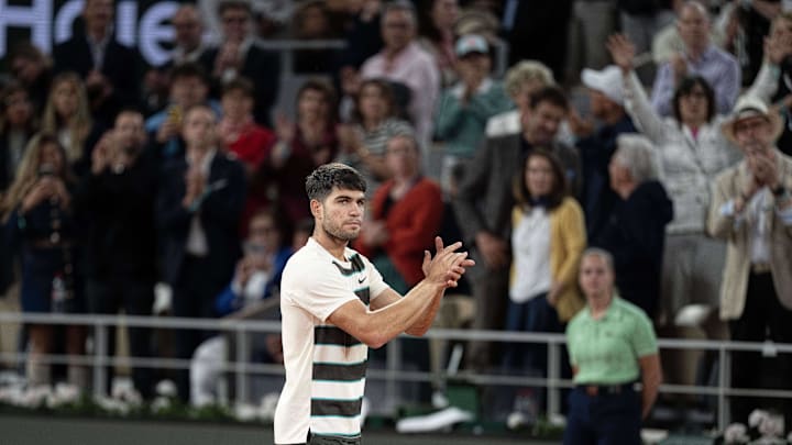 Jun 6, 2025; Paris, FR;  Carlos Alcaraz of Spain gives  Lorenzo Musetti of Italy a hand after Musetti retired in the fourth set of their match on day 13 at Roland Garros Stadium. Mandatory Credit: Susan Mullane-Imagn Images
