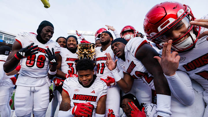 Nov 30, 2024; Lexington, Kentucky, USA; Louisville Cardinals defensive lineman Ramon Puryear (41) and Louisville Cardinals defensive back Jathan Hatch (31) hold up the Governor’s Cup trophy after winning against the Kentucky Wildcats at Kroger Field. Mandatory Credit: Jordan Prather-Imagn Images