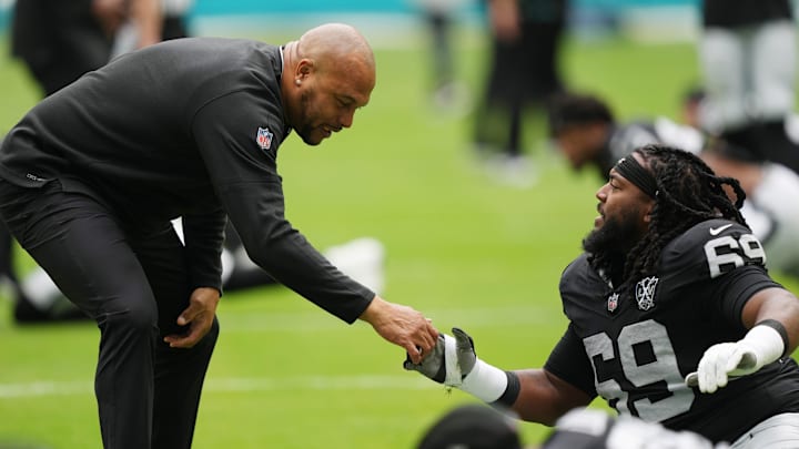 Nov 17, 2024; Miami Gardens, Florida, USA; Las Vegas Raiders defensive tackle Adam Butler (69) is greeted by head coach Antonio Pierce during pregame warm-ups at Hard Rock Stadium. Mandatory Credit: Jim Rassol-Imagn Images