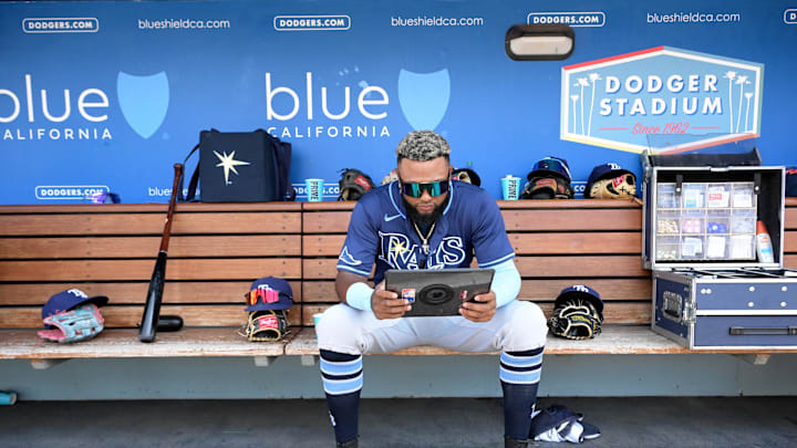 Tampa Bay Rays third baseman Junior Caminero (13) checks his iPad in the dugout against the Los Angeles Dodgers at Dodger Stadium in 2024.