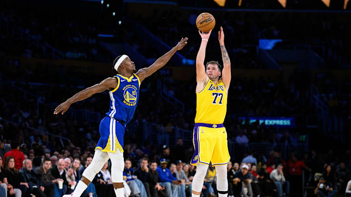 Oct 21, 2025; Los Angeles, California, USA; Los Angeles Lakers guard Luka Doncic (77) shoots over Golden State Warriors forward Jimmy Butler III (10) during the first half at Crypto.com Arena. Mandatory Credit: William Liang-Imagn Images