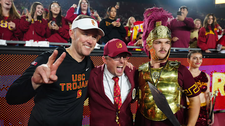 Nov 29, 2025; Los Angeles, California, USA; Southern California Trojans head coach Lincoln Riley (left) poses with Spirit of Troy marching band director James Vogel (center) and mascot Tommy Trojan after the game against the UCLA Bruins at United Airlines Field at Los Angeles Memorial Coliseum. Mandatory Credit: Kirby Lee-Imagn Images