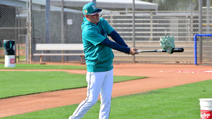 Feb 12, 2026; Peoria, AZ, USA;  Seattle Mariners bench coach Manny Acta (14) practices his golf swing with a  bat during a Spring Training workout at Peoria Sports Complex. Mandatory Credit: Matt Kartozian-Imagn Images