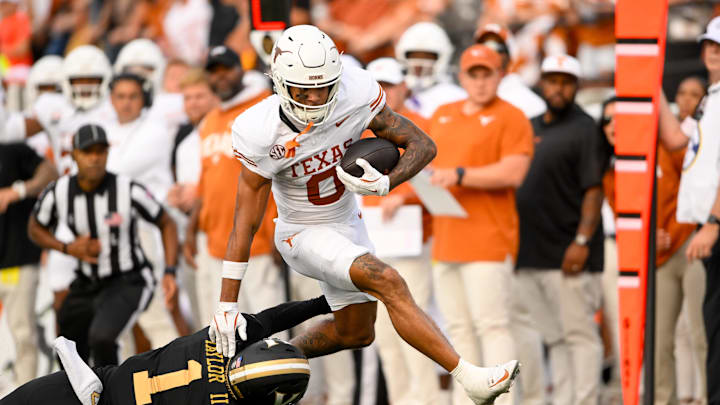 Oct 26, 2024; Nashville, Tennessee, USA; Texas Longhorns wide receiver DeAndre Moore Jr. (0) stiff arms Vanderbilt Commodores safety CJ Taylor (1) as he crosses the goal line during the first half at FirstBank Stadium. Mandatory Credit: Steve Roberts-Imagn Images